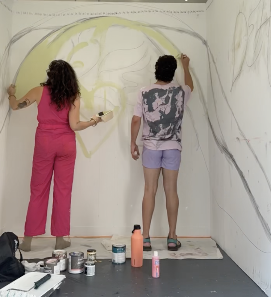 Quincee working with a client on a large wall mural